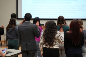 A photo of USG members reciting a pledge at a senate meeting