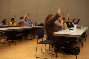 A photo of USG members voting at a senate meeting